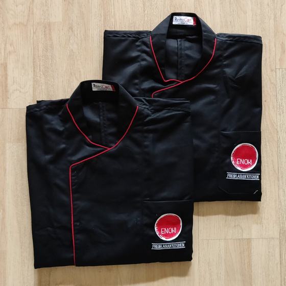 Black wrap-front chef coats with red piping along the crossover and a red round logo, custom chef uniforms made for Enoki Kitchen by RestroCart