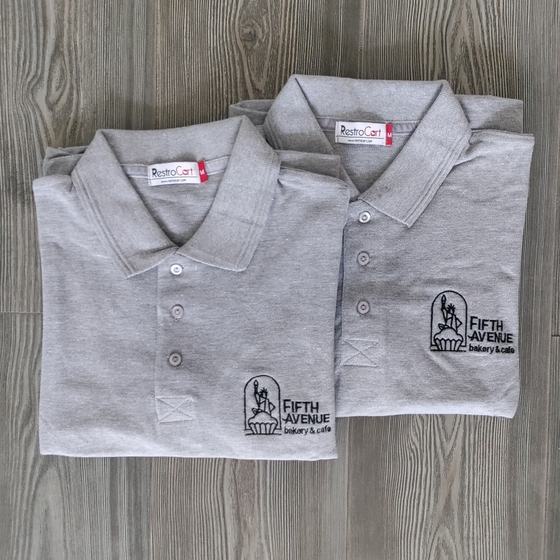 Two grey melange polo t-shirts with black embroidered bakery logo, folded, custom made for Fifth Avenue Bakery by RestroCart, New Delhi