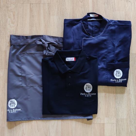 Grey waist apron, navy polo t-shirt and navy chef coat with white embroidered round logo, custom made for Fork n Knives by RestroCart, New Delhi
