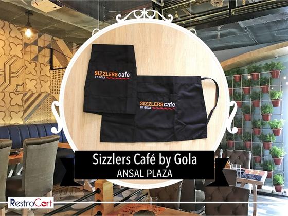 Two black waist aprons with orange and white printed logo, one with long ties, laid flat, custom made for Gola Sizzlers by RestroCart, New Delhi