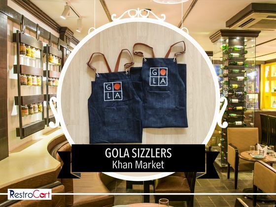 Two navy denim bib aprons with brown leather neck straps and white printed logo, laid flat, custom made for Gola Sizzlers by RestroCart, New Delhi