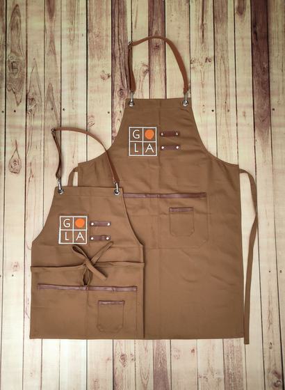 Golden brown canvas apron pair with leather straps and printed grid logo with orange dot, custom made by RestroCart, New Delhi