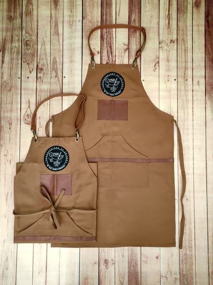 Brown canvas apron pair with black round embroidered logo and leatherette patches, custom made by RestroCart, New Delhi