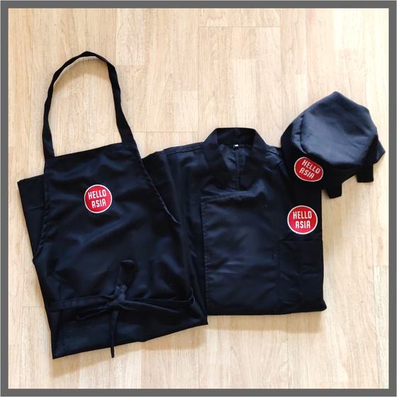 Navy bib apron, chef coat and skull cap with round red logo patch, framed with grey border, custom made for Hello Asia by RestroCart, New Delhi
