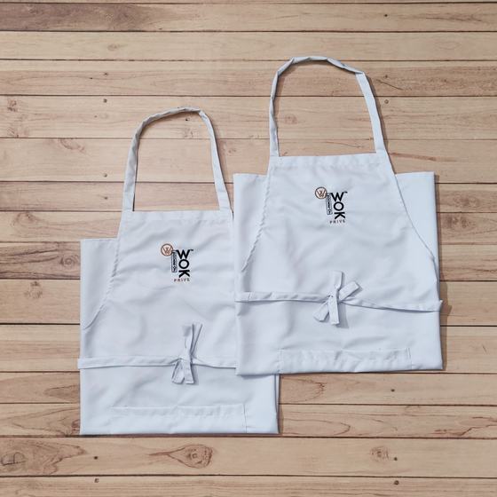 Two white bib aprons with printed logo on chest and waist ties, laid flat on wooden floor, custom made for House of Wok Prive by RestroCart, New Delhi