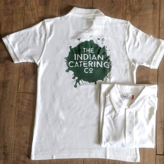 White polo T-shirts with large green splash logo printed on back, one folded, custom made for Indian Catering Company by RestroCart, New Delhi
