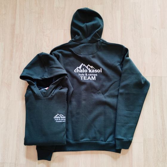 Two dark green hoodies with white printed mountain logo and TEAM text on back, one folded, custom made for Kasol by RestroCart, New Delhi