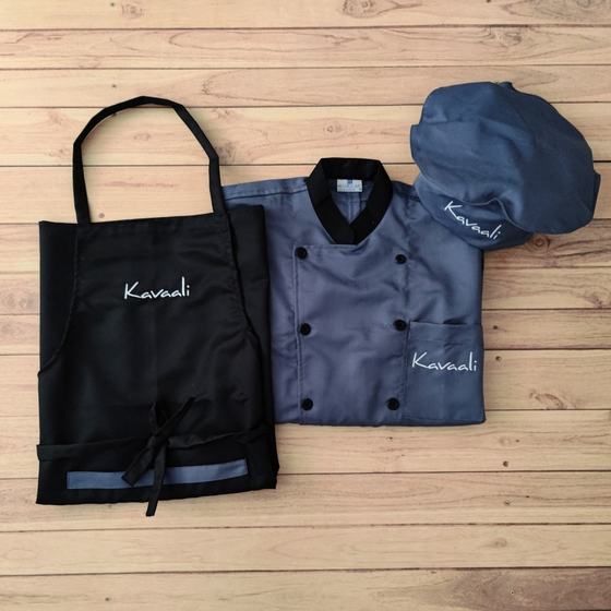 Grey chef coat with black collar and buttons, black bib apron and grey cap, all with script logo, custom made for Kavaali by RestroCart, New Delhi