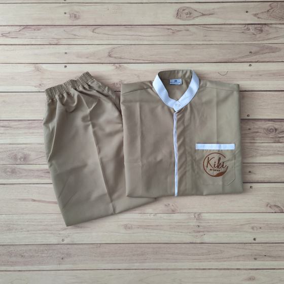 Beige housekeeping tunic with white mandarin collar and placket plus matching trousers, pocket logo, custom made for Kiki Bar by RestroCart, New Delhi