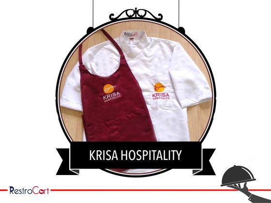 White chef coat with orange logo beside a maroon bib apron with matching logo, custom made for Krisa Hospitality by RestroCart, New Delhi