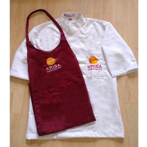 White chef coat with maroon bib apron, both with orange and pink embroidered logo, custom made for Krisa Hospitality by RestroCart, New Delhi