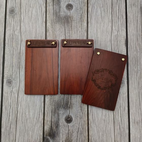 Three dark wood menu boards with brass screws and engraved wreath logo, on grey planks, custom made for L'Papillae by RestroCart, New Delhi