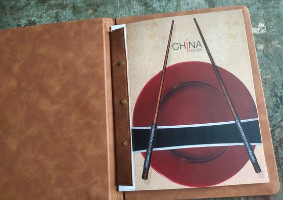 Open tan leatherette menu folder with screw-post binding holding a printed menu page, custom made by RestroCart, New Delhi