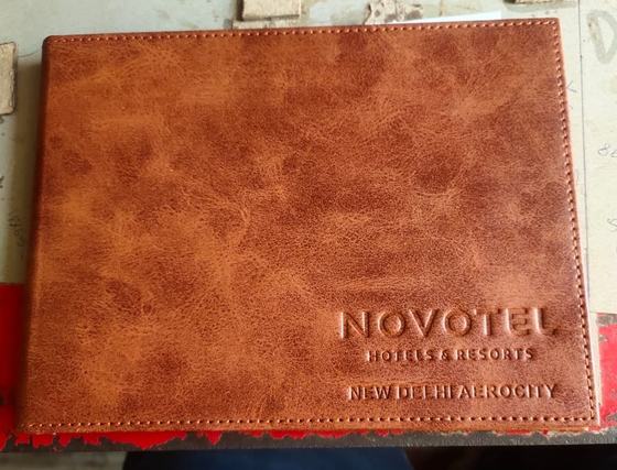 Distressed tan leatherette landscape menu folder with debossed hotel name and location, custom made by RestroCart, New Delhi