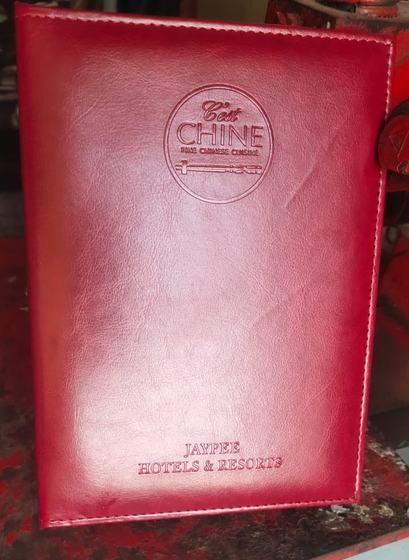 Red leatherette menu folder with stitched edges, debossed round logo and debossed hotel name, custom made by RestroCart, New Delhi