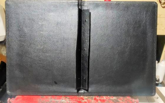 Inside of an open black leatherette menu folder showing stitched edges and screw-post spine strip, custom made by RestroCart, New Delhi