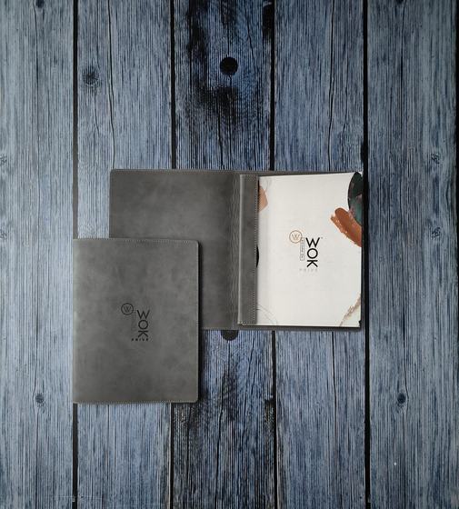 Grey leatherette menu covers with debossed logo, one open on screw posts showing printed menu, custom made by RestroCart, New Delhi