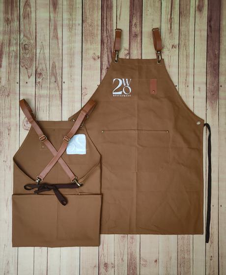 Golden brown canvas bib apron with white logo and crossback leather strap apron, custom made by RestroCart, New Delhi