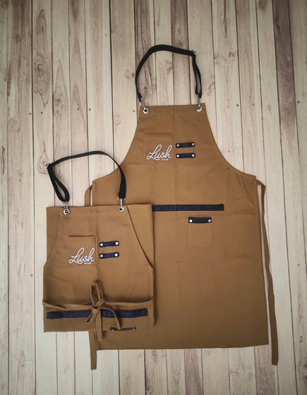 Golden brown canvas apron pair with black straps, pen loops and white script logo, custom made by RestroCart, New Delhi
