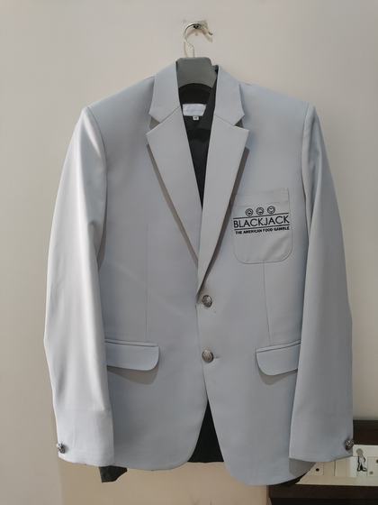 Light grey single-breasted manager blazer with black embroidered pocket logo, on a hanger, custom made by RestroCart, New Delhi