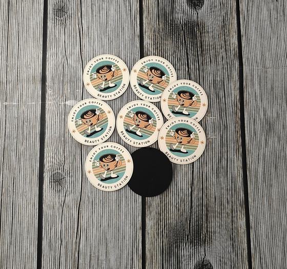 Round cream MDF coasters with retro cartoon coffee mascot print and a black underside shown, custom made by RestroCart, New Delhi