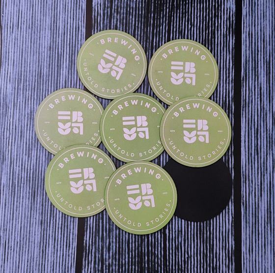 Round sage green MDF coasters with pink printed brewing logo and one black back side, custom made by RestroCart, New Delhi