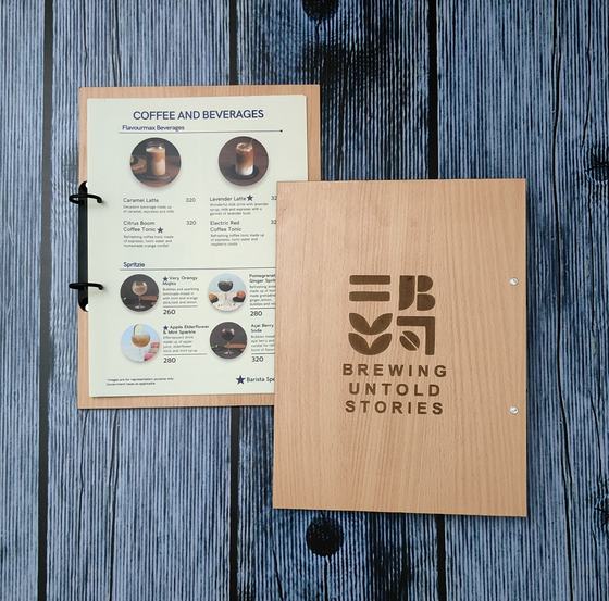 Light oak MDF menu board with large engraved logo beside a printed coffee and beverages page, custom made by RestroCart, New Delhi