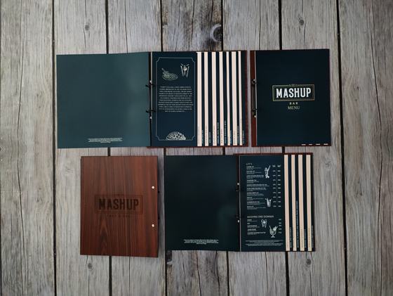 Dark wood grain and teal ring bound bar menus shown open with striped printed pages, on grey wood, custom made by RestroCart, New Delhi
