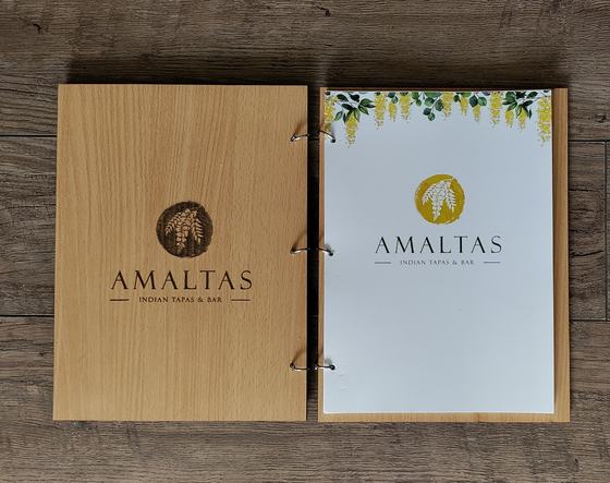 Light wood MDF menu folder with engraved logo, opened to white ring-bound printed pages, custom made by RestroCart, New Delhi