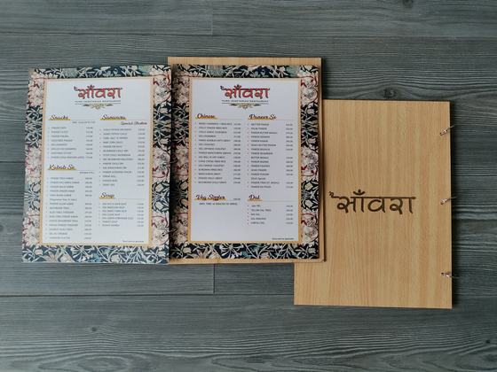 Wood finish MDF menu cover with engraved Devanagari name beside two floral bordered printed menus, custom made by RestroCart, New Delhi