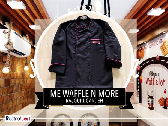 Black chef coat with pink piping and small logo on the chest pocket, laid flat, custom made for Me Waffle N More by RestroCart, New Delhi
