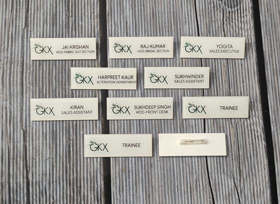 White rectangular staff name badges with green logo, printed names and job titles, custom made by RestroCart, New Delhi