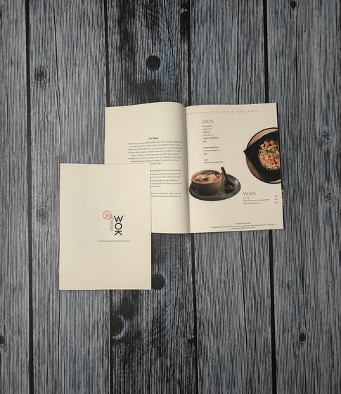 Loose printed paper menu with cream cover and open inner spread showing dish photos and prices, custom made by RestroCart, New Delhi