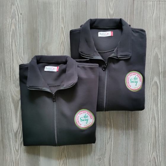Two black fleece zip jackets with round embroidered badge logo on chest, folded, custom made for Pizzeria Da Susy by RestroCart, New Delhi