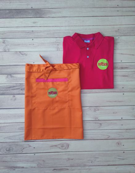 Pink polo t-shirt and orange waist apron with pink pocket trim, both with round green logo badge, custom made by RestroCart, New Delhi