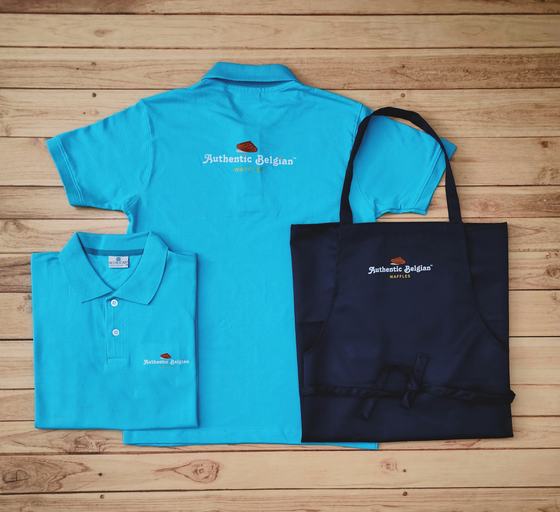 Turquoise blue polo t-shirts with chest print and navy bib apron with matching logo, laid flat, custom made by RestroCart, New Delhi