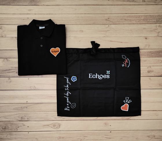 Black polo t-shirt with orange heart patch and black waist apron with white print and doodles, custom made by RestroCart, New Delhi