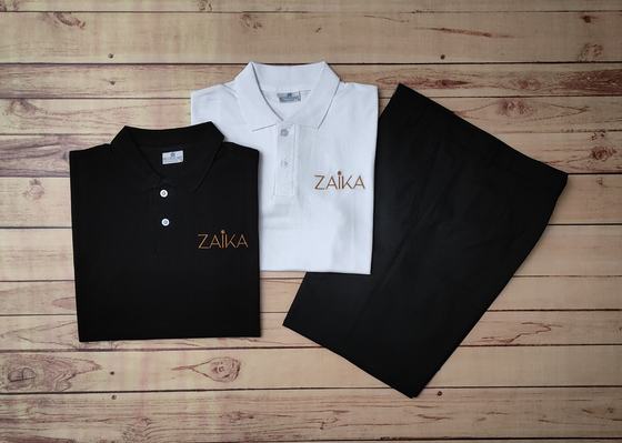 Black and white polo t-shirts with gold embroidered logo and black trousers, folded flat, custom made by RestroCart, New Delhi