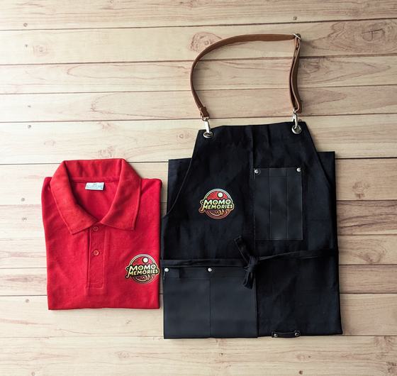 Red polo t-shirt with round logo patch and black denim bib apron with brown leather neck strap, custom made by RestroCart, New Delhi