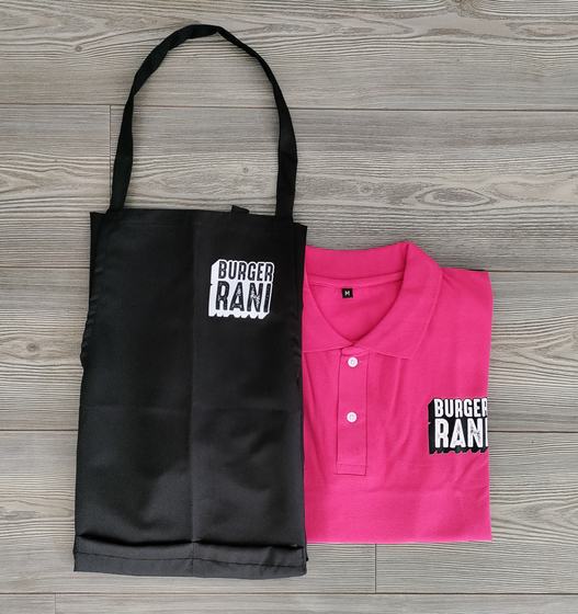 Black bib apron and pink polo t-shirt, both with bold black and white printed text logo, custom made by RestroCart, New Delhi