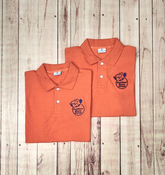 Two orange polo t-shirts with navy embroidered round chef logo, folded and overlapping, custom made by RestroCart, New Delhi