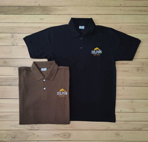 Black and brown polo t-shirts with yellow and white embroidered hotel logo on the chest, laid flat, custom made by RestroCart, New Delhi
