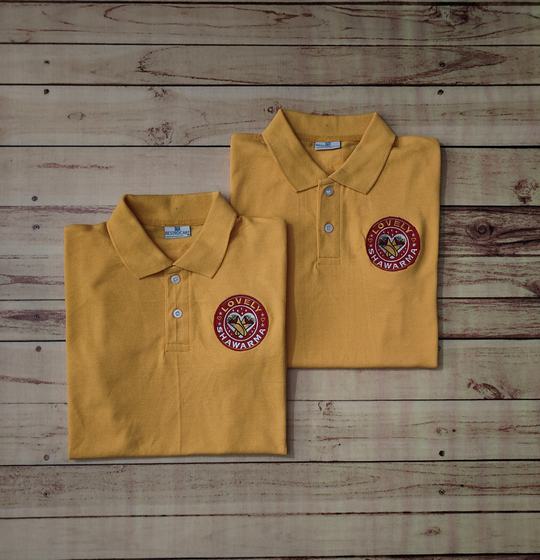 Pair of folded mustard yellow polo t-shirts with round maroon embroidered badge logo on the chest, custom made by RestroCart, New Delhi