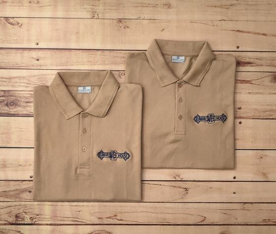 Pair of folded beige polo t-shirts with black and white embroidered banner logo on the chest, custom made by RestroCart, New Delhi