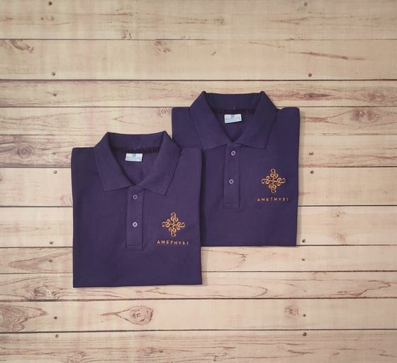 Pair of folded purple polo t-shirts with gold embroidered ornamental logo and wordmark, on wood, custom made by RestroCart, New Delhi
