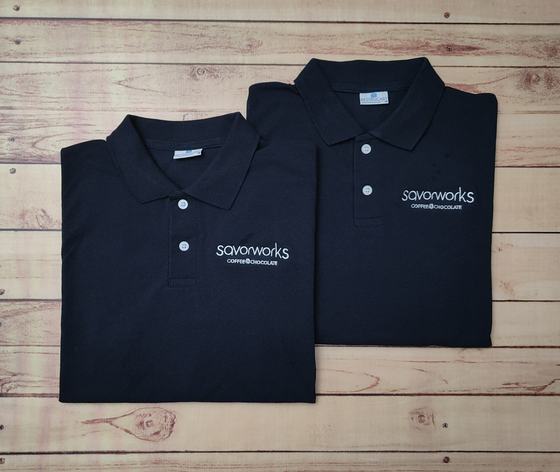 Pair of folded navy polo t-shirts with white printed coffee and chocolate wordmark on the chest, custom made by RestroCart, New Delhi