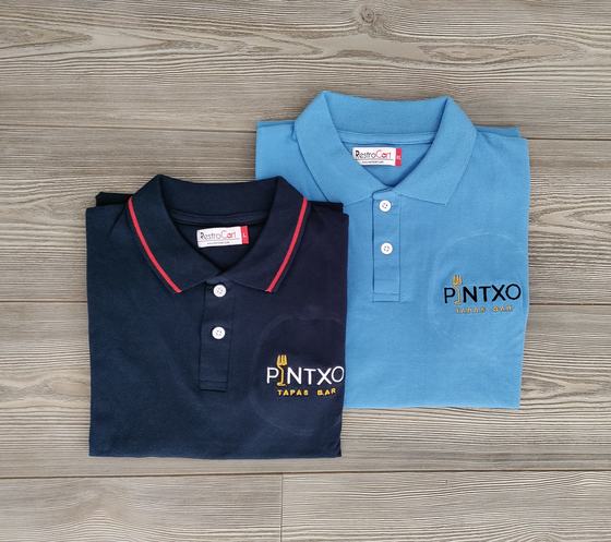Navy polo with red tipped collar and sky blue polo, both with gold and black printed logo, custom made by RestroCart, New Delhi