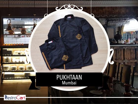 Navy chef coat with gold side stripe and gold embroidered logo with navy trousers, folded, custom made for Pukhtaan by RestroCart, New Delhi