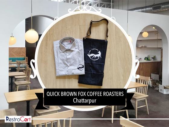 White service shirt with small fox logo beside a navy bib apron with white fox print, custom made for Quick Brown Fox by RestroCart, New Delhi