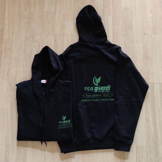 Two black hoodies with large green printed logo on back and small chest logo, laid flat, custom made by RestroCart, New Delhi